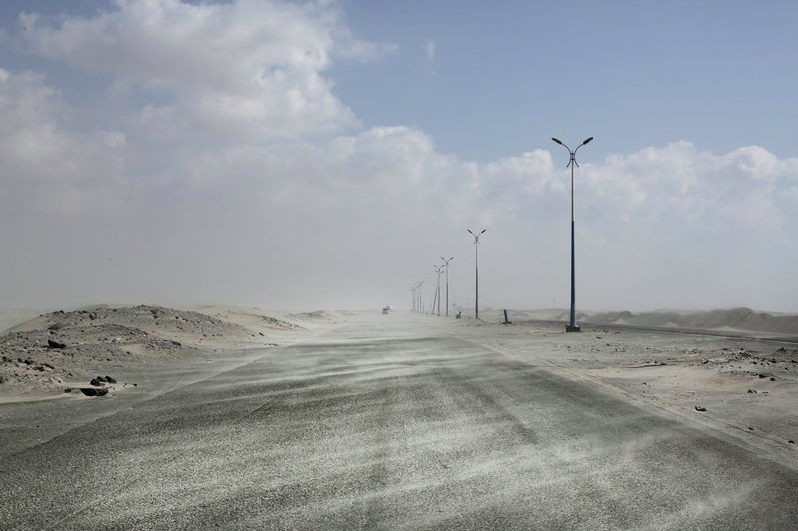This Feb. 15, 2018, photo shows sand drifting over an empty highway from Abyan to Aden in Yemen. Violence, famine and disease have ravished the country of some 28 million, which was already the Arab world’s poorest before the conflict began. The conflict pits a U.S.-backed, Saudi-led coalition supporting the internationally recognized government, which has nominally relocated to Aden but largely lives in exile, against rebels known as Houthis. Image by Nariman El-Mofty. Yemen, 2018. 
