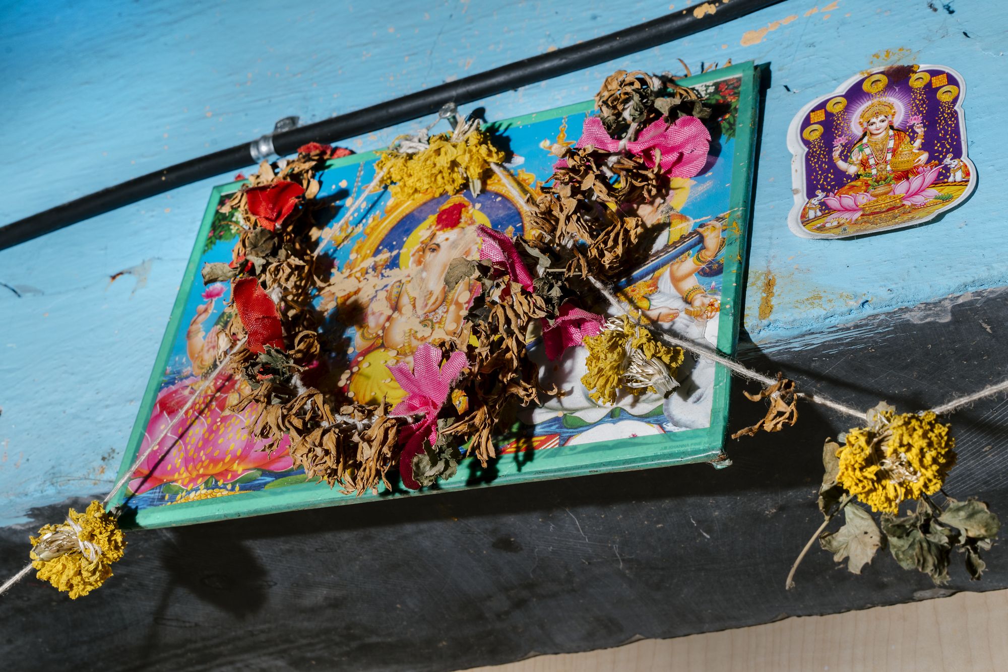 Garlands and images of deities hang over the doorway of an apartment in the Dharavi area of Mumbai, India. This particular part of Dharavi is home to many hijras, a formally recognized third gender in India. Image by Jake Naughton and Aarti Singh. India, 2018.