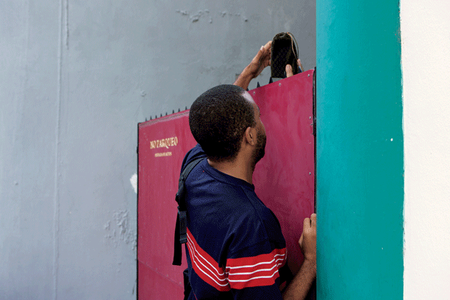Maykel Molina Gutiérrez delivers El Paquete to a customer during his weekly round. Image by Alexa Hoyer. Cuba. 
