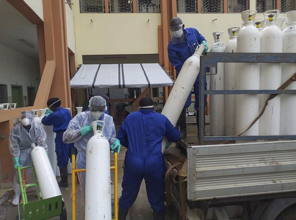 Medical workers offload cylinders of oxygen at the Donka public hospital where coronavirus patients are treated in Conakry, Guinea, on Wednesday, May 20, 2020. Before the coronavirus crisis, the hospital in the capital was going through 20 oxygen cylinders a day. By May, the hospital was at 40 a day and rising, according to Dr. Billy Sivahera of the aid group Alliance for International Medical Action. Oxygen is the the facility's fastest-growing expense, and the daily deliveries of cylinders are taking their toll on budgets. Image by Youssouf Bah / AP Photo. Guinea, 2020.