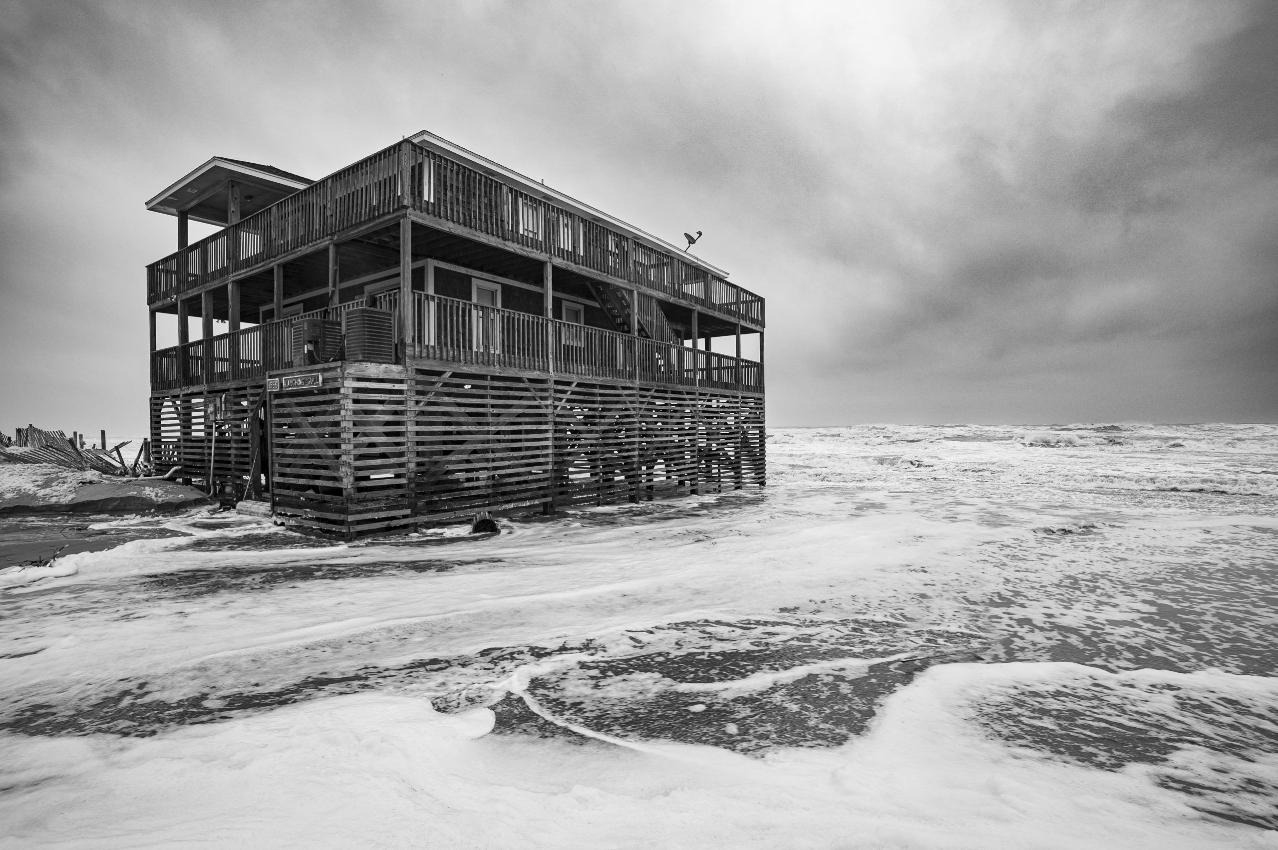 Surf washes around an Outer Banks home during a nor’easter in November 2019. Image by Jared Lloyd. United States, 2019.