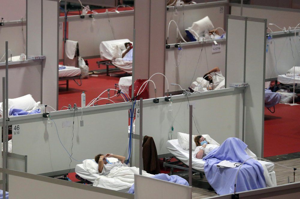 FILE - In this Thursday, April 2, 2020 file photo, patients lie in beds at a temporary field hospital in the Ifema convention center in Madrid, Spain. As coronavirus deaths climbed, engineers laid 7 kilometers (4 miles) of tubing in less than a week to give 1,500 beds in the impromptu facility a direct supply of pure oxygen. Image by Manu Fernandez / AP Photo. Spain, 2020