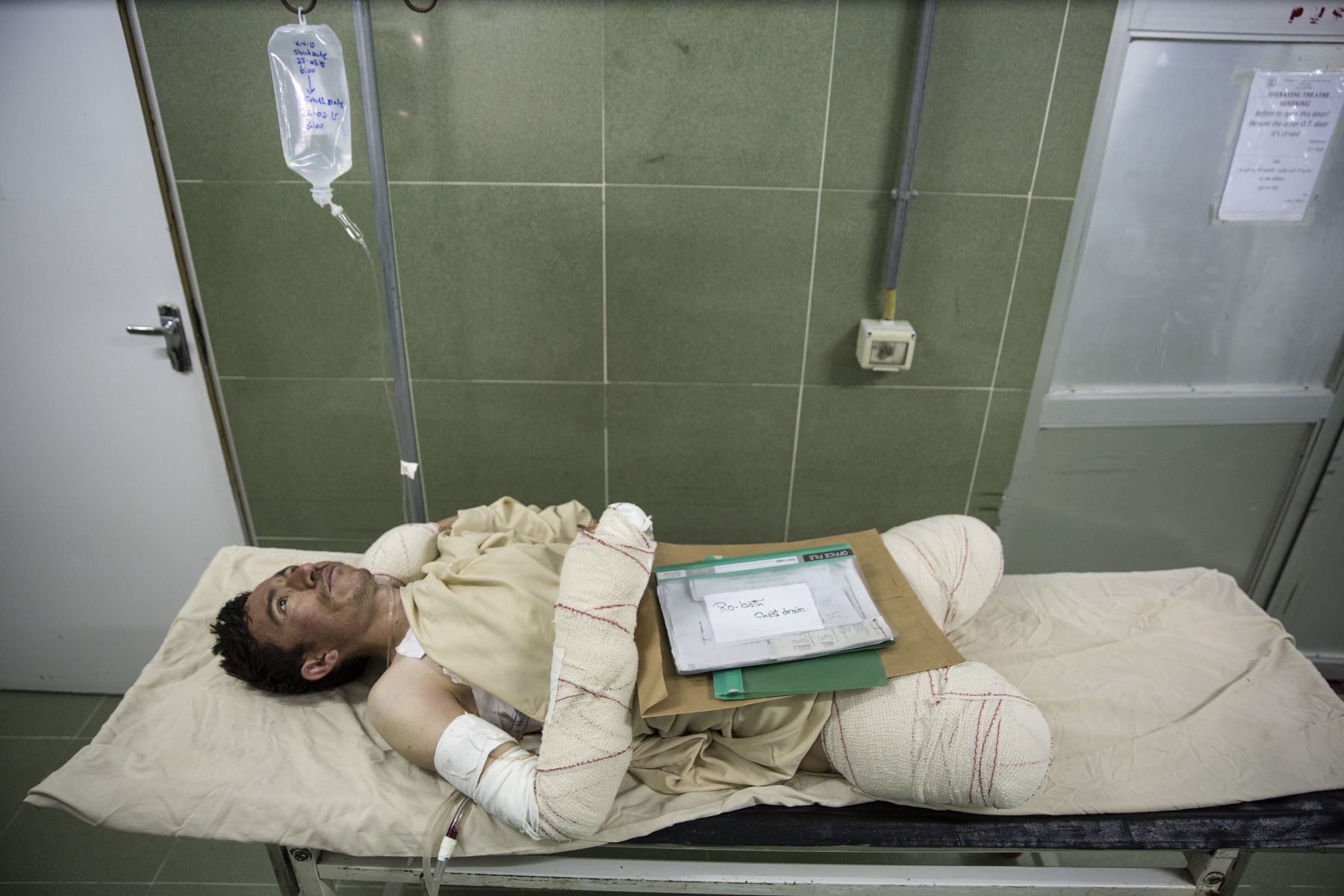 Sayed Malik, 25, waits to go into surgery. He lost his legs while demining, as a ANA soldier in Sangin. Lashkar Gah, Afghanistan. Image by Paula Bronstein. Afghanistan, 2015.