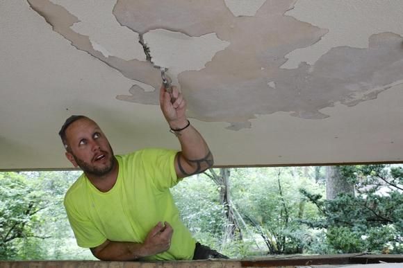 Donald Thompson of Machesney Park scrapes and repairs plaster on the ceiling of the carport on Tuesday at the Laurent House Museum in Rockford. Image by Susan Moran/Rockford Register Star. United States, 2020.