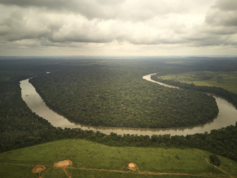 Visão aérea de um trecho no rio dos Peixes onde se pode ver o contraste entre a área desmatada na margem não indígena do rio e a área preservada dentro da Terra Indígena na outra margem. Image by: Pablo Albarenga. Brazil, 2019. 