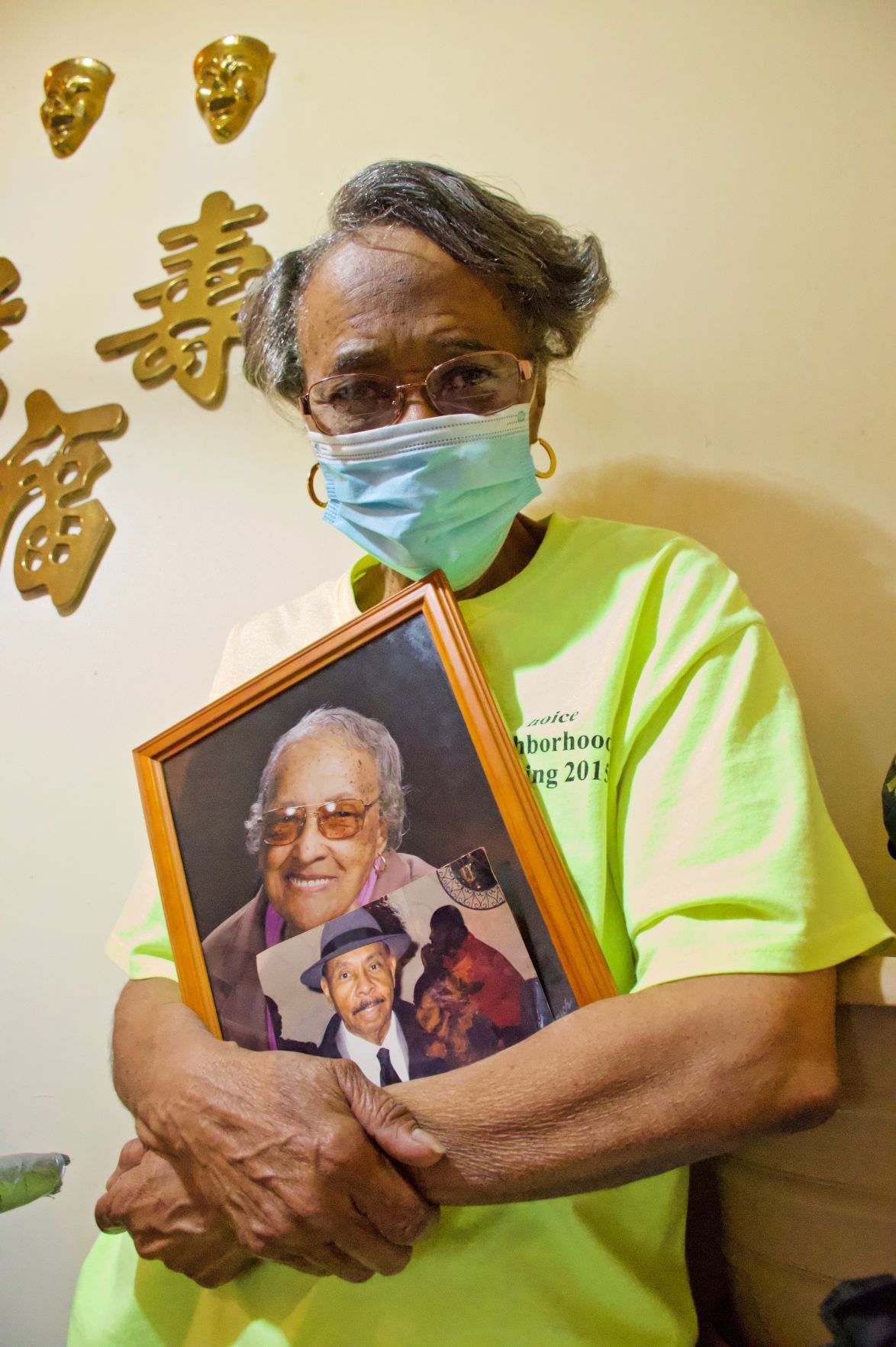Valerie Nichols poses with photos of her mother, Willie Mae Nichols, and father, Anthony Nichols at her home in Preservation Square. Her father is deceased and her mother is living at Grand Manor Nursing and Rehabilitation Center. Image by Wiley Price/St. Louis American. United States, 2020.