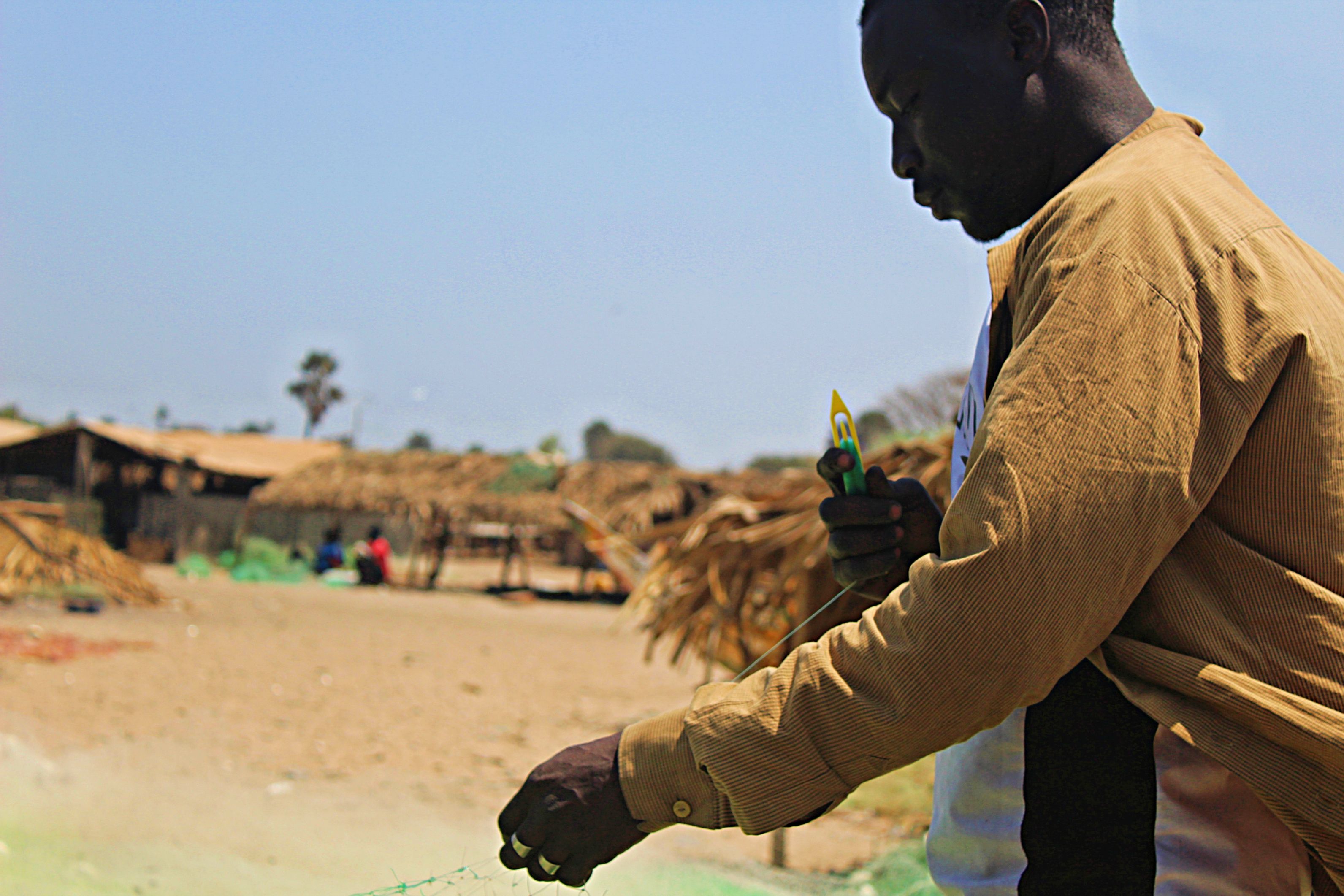 Edrissa Sackh and his captain Abdulai Camara mend their fishing net on Gunjur beach. These small-scale fishermen catch the majority of fish critical to food security. Image by Nosmot Gbadamosi. Gambia, 2018.