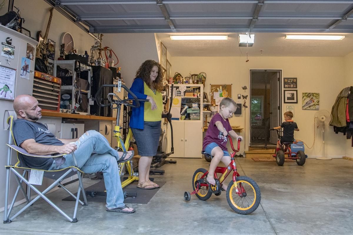Elias and Crystal Camacho watch their sons Elias, 4, left, and Asher, 7, play on their bikes in the garage of their Swannanoa home on June 30, 2020. Before finding a new day care for Elias after the one he was attending closed, Camacho and her husband had to take turns staying home half days or take the kids to work with them. Image by Angeli Wright/Asheville Citizen Times/North Carolina News Collaborative. United States, 2020.