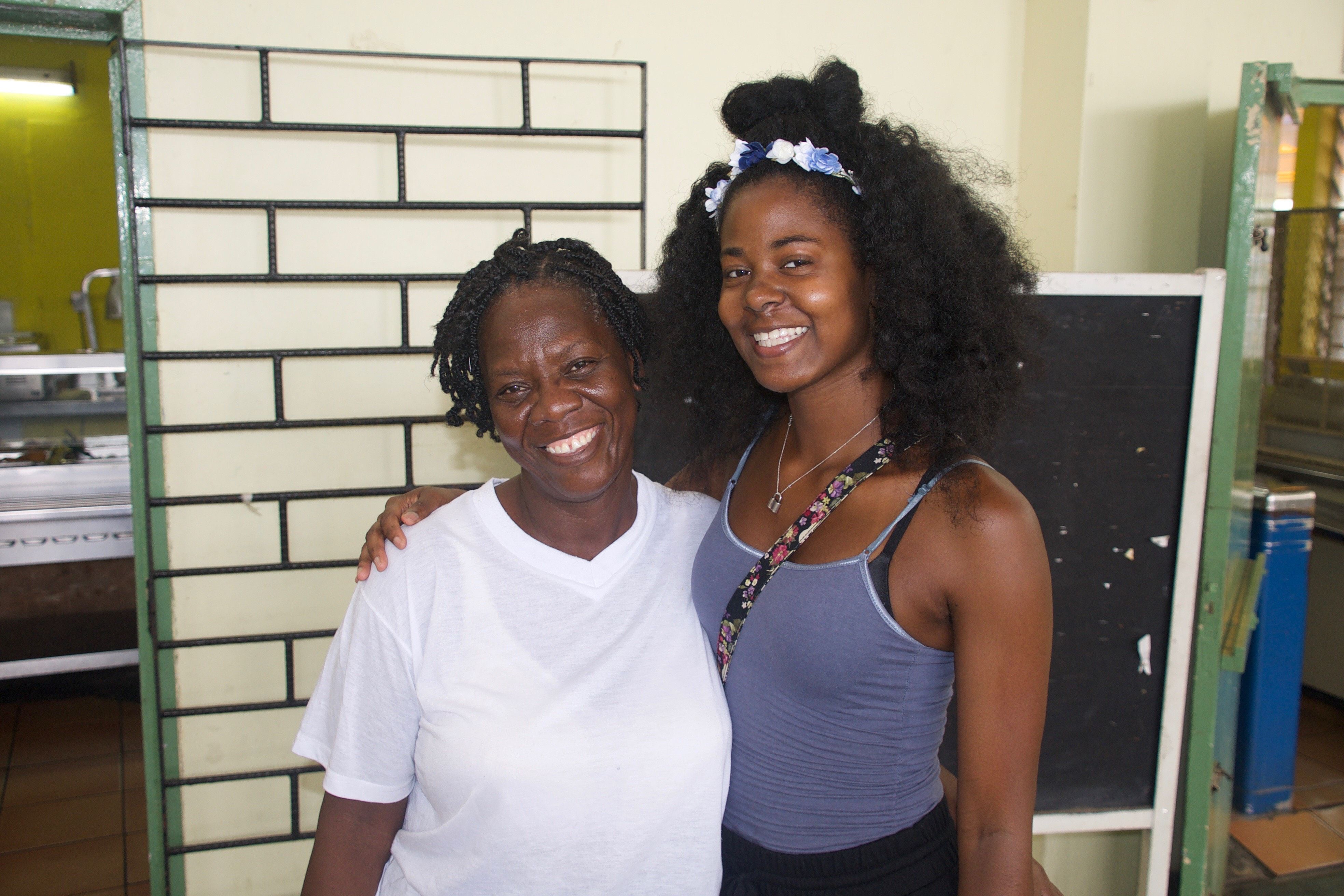 Monica Long poses with cafeteria worker, Yvonne Grant. Image by James D. McJunkins, Sr., and Monica Long. Jamaica, 2018.