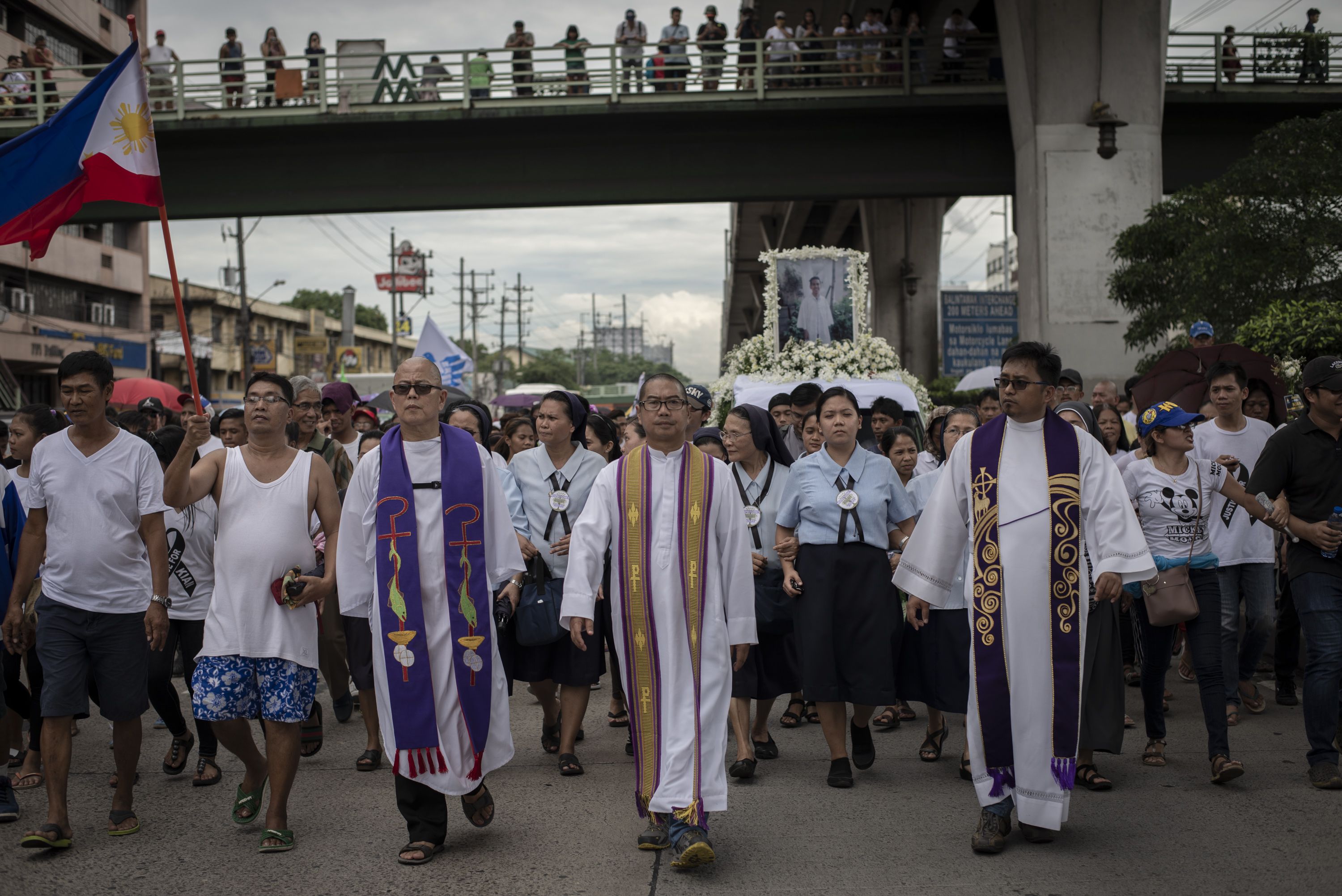 Catholic priests Robert Reyes (left) and Flavie Villanueva (center) lead the funeral procession of seventeen-year-old Kian Loyd delos Santos, who was shot and killed by police. Image by Eloisa Lopez. Manila, 2017.