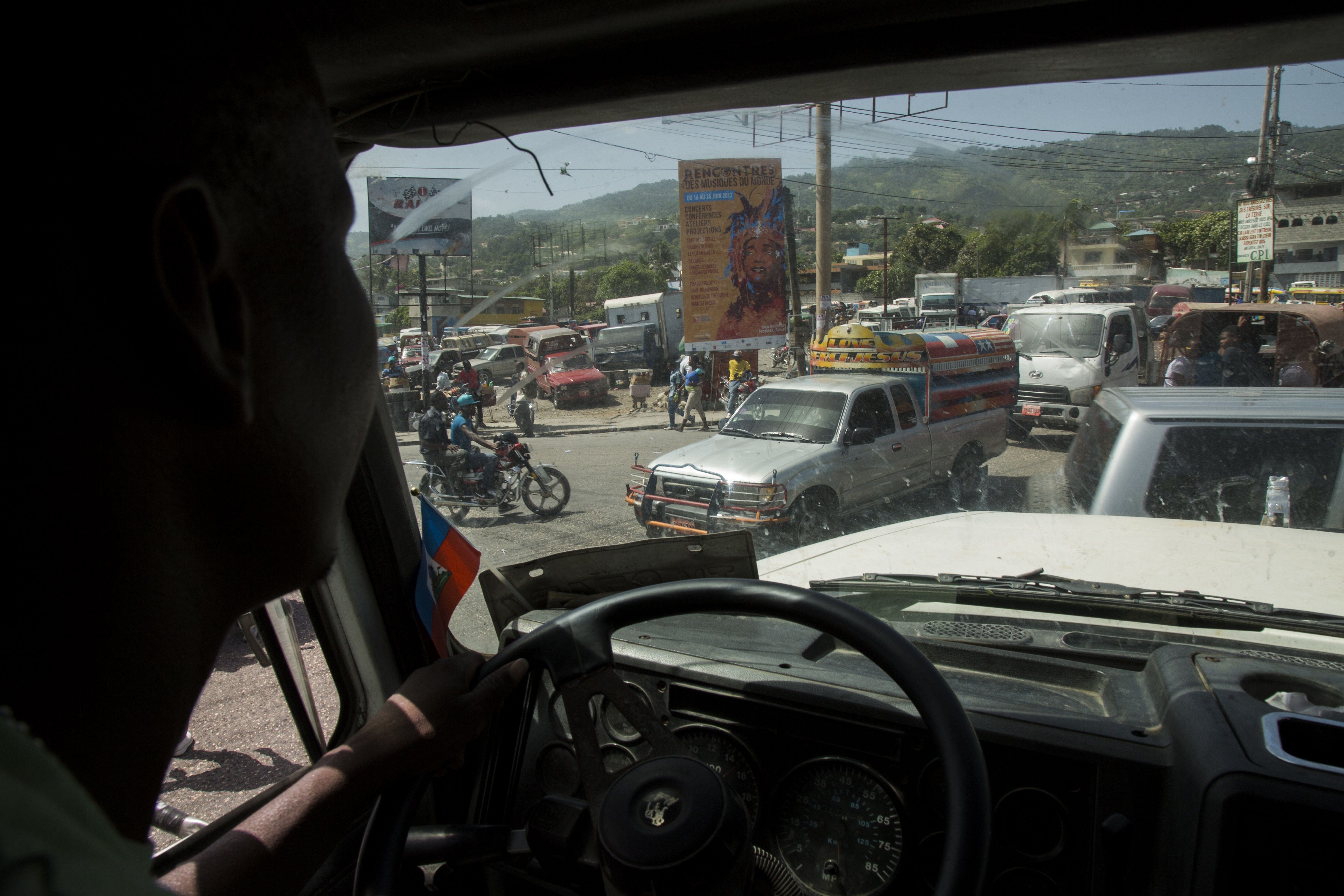 Elide Jean Petrus, 46, drives a truck through traffic in downtown Port-au-Prince, Haiti. Image by Marie Arago. Haiti, 2017.