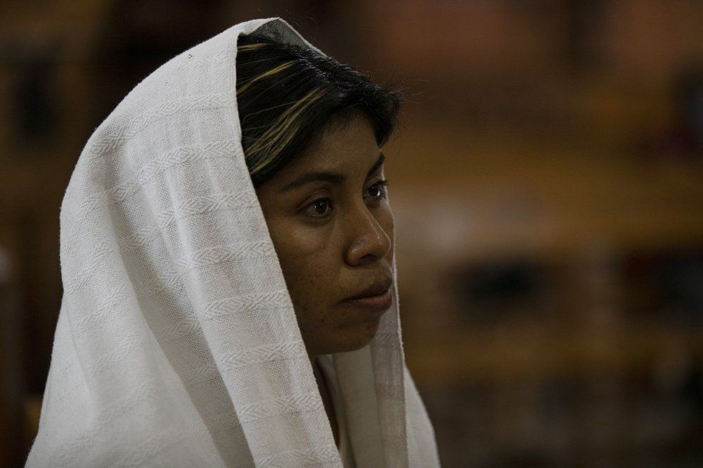 A woman attends Mass at church in San Jeronimo Xayacatlan, a town in Mexico from where nearly a third have emigrated to New York, Thursday, June 25, 2020. From the speakers on the church's bell towers, prayers ring out daily, pleading for the end of the pandemic, and praying for its victims. Image by Fernando Llano/AP Photo. Mexico, 2020.