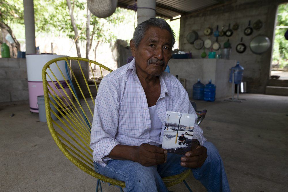 Wilfrido Martinez holds a photo of his 39-year-old son Mauricio, who died from COVID-19 in New York, as he poses for a portrait at his home in San Jeronimo Xayacatlan, Mexico, Friday, June 26, 2020. Martinez said his son, who worked in a restaurant kitchen in New York, was diabetic and didn't protect himself against infection. Until his son died, he himself had believed the virus was a fraud perpetrated by politicians for reasons he did not understand. Image by Fernando Llano/AP Photo. Mexico, 2020.