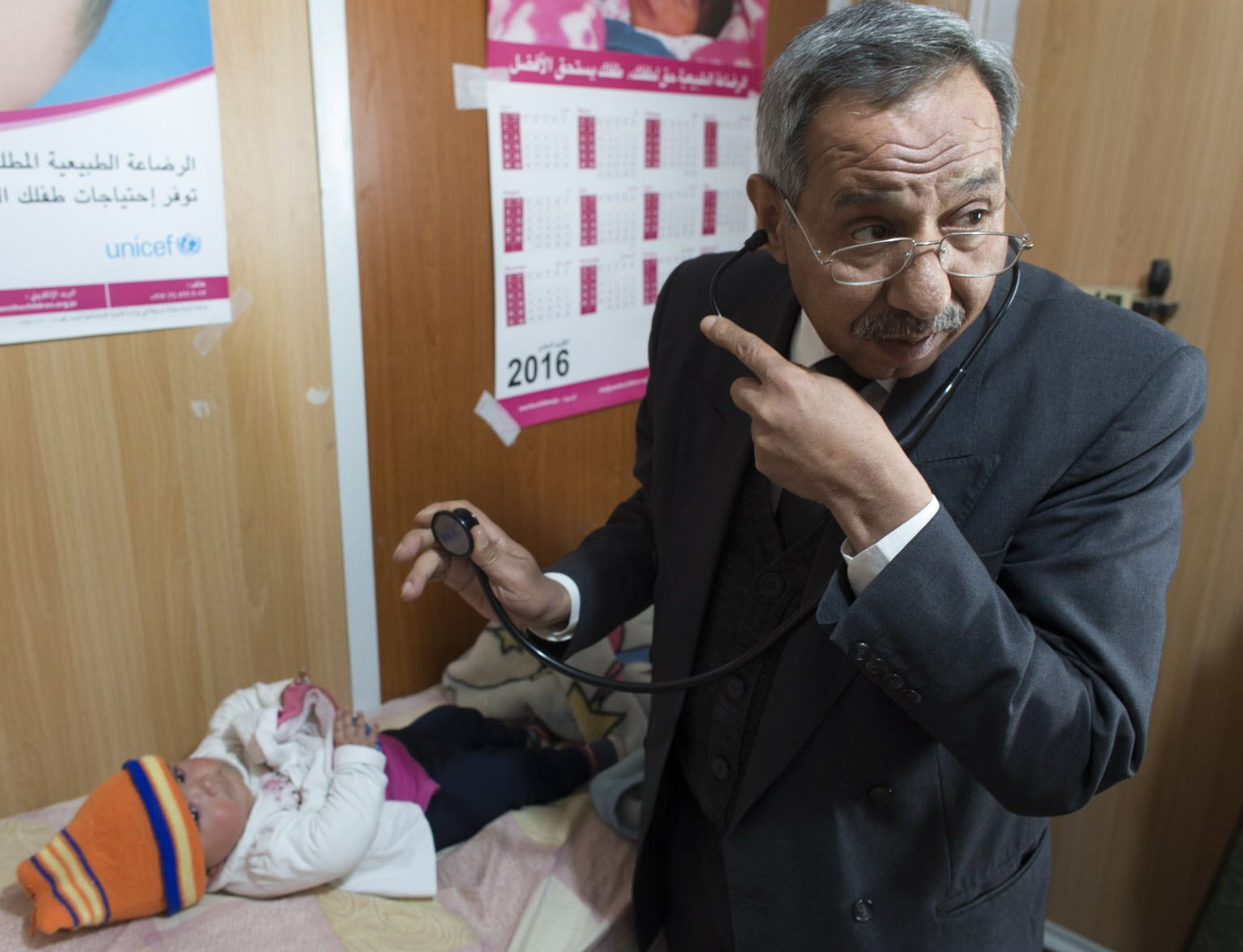 Clinic director and family practice physician Hussein Al Seibrani examines an infant. Seibrani is also a refugee and was a torture victim in Syria. Image by Mark Hoffman. Jordan, 2016.