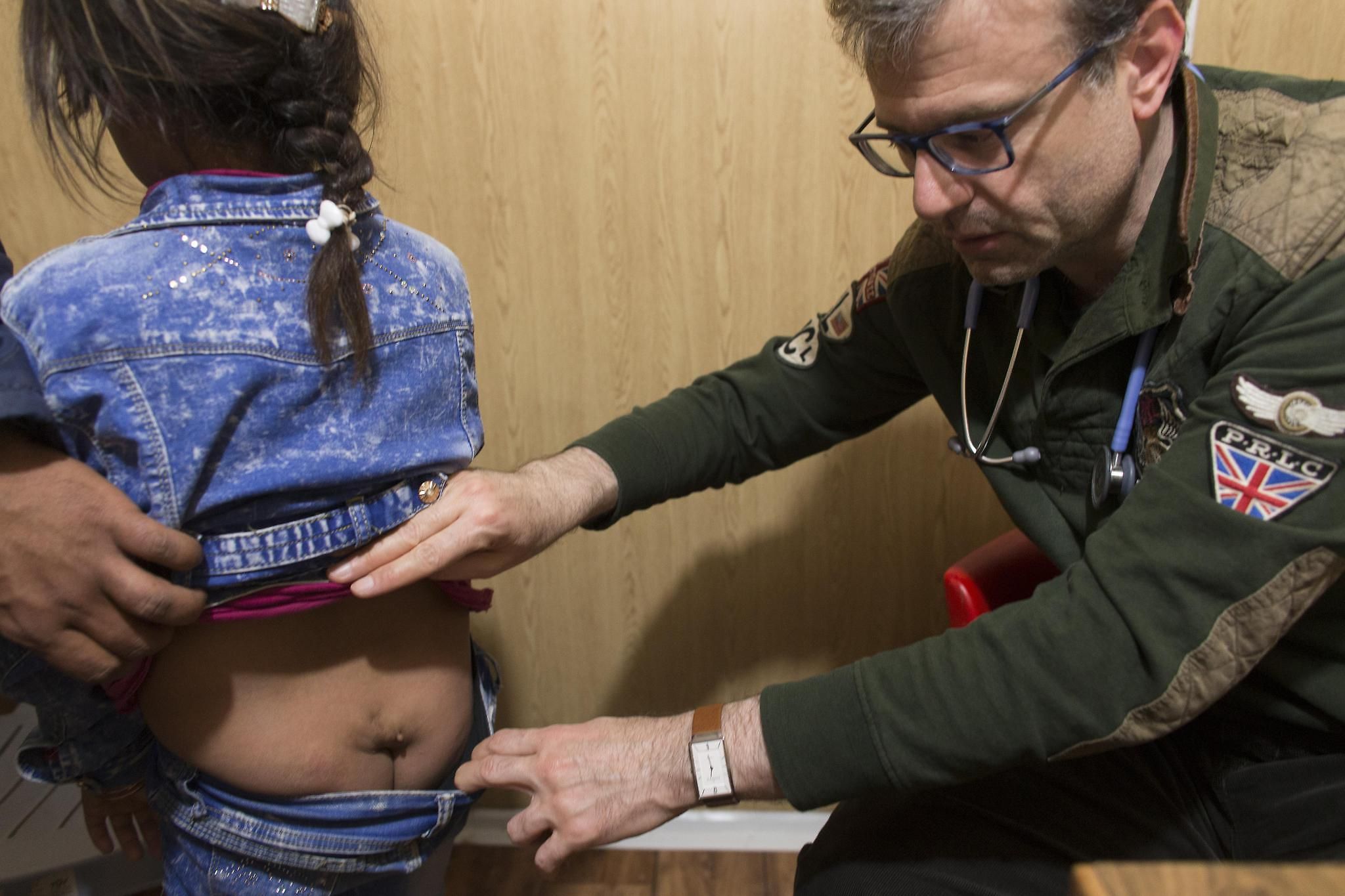 Brookfield pediatric neurologist Tarif Bakdash examines 8-year-old Sandy Al Mekdad who has condition known as a tethered spinal cord. She now suffers from incontinence and leg pain. The defect can be corrected by surgery,but the procedure cannot be done inside the camp. Image by Mark Hoffman. Jordan, 2016.