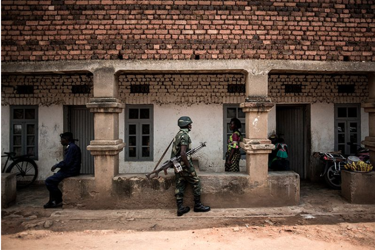 A soldier stands guard outside a centre where health workers are vaccinating people against the Ebola virus. Image by John Wessels. Democratic Republic of Congo, 2019.