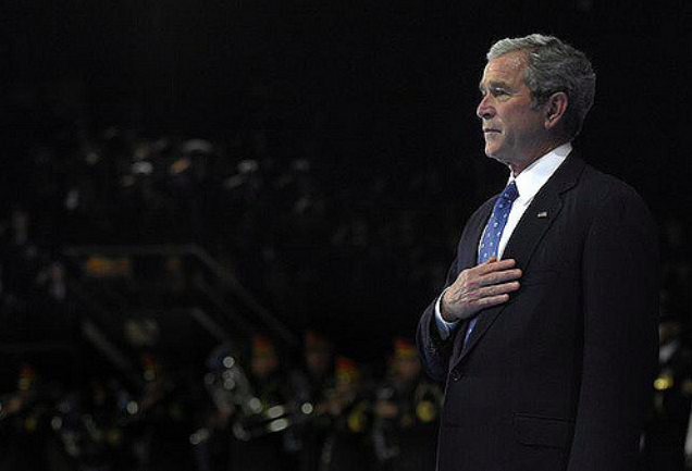 President George W. Bush places his hand on his heart while the national anthem plays during the Armed Forces Full Honor Farewell to President George W. Bush on Fort Myer, Va., Jan. 6, 2009. CC BY 2.0. United States, 2009.