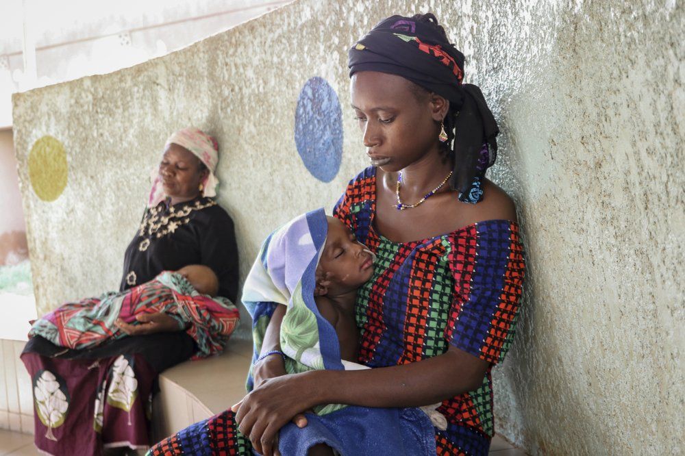 Fatima Li, 20, foreground, holds her two-year-old son, Hama Sow, as he is treated with a feeding tube for malnourishment, as Hadiara Ouedraogo, left, sits with her granddaughter, Fatimata Ouedrago, 2, who has edema due to severe malnourishment, at Yalgado Ouedraogo University in Ouagadougou, Burkina Faso on Monday, June 22, 2020. In Burkina Faso one in five young children is chronically malnourished. Food prices have spiked, and 12 million of the country’s 20 million residents don’t get enough to eat. Image by Sam Mednick/AP Photo. Burkina Faso, 2020.

