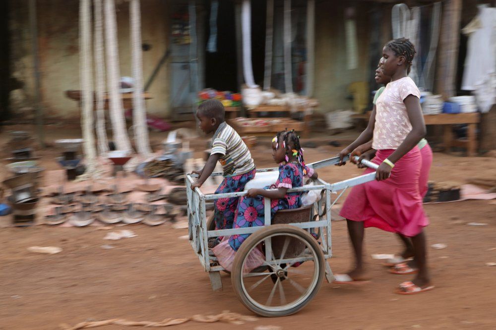 Girls push children in a cart near the market in the town of Hounde, Tuy Province, in southwestern Burkina Faso on Thursday, June 11, 2020. Image by Sam Mednick/AP Photo. Burkina Faso, 2020.
