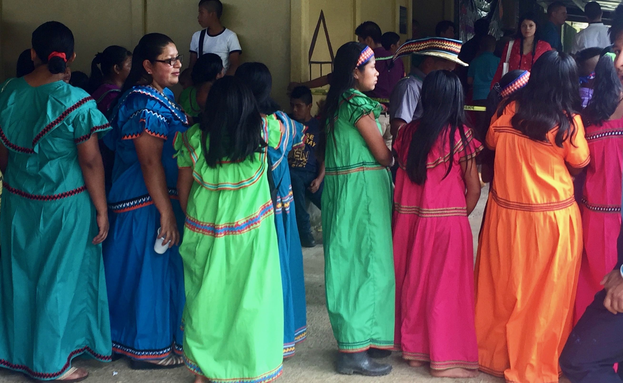 In southern Costa Rica, long brightly colored dresses are commonly associated with the Ngäbe-Buglé. A group of young Ngäbe-Buglé women dressed in traditional clothing watch a dance performance produced by the elementary school in their community. Image by Samira Tella. Costa Rica, 2018. 