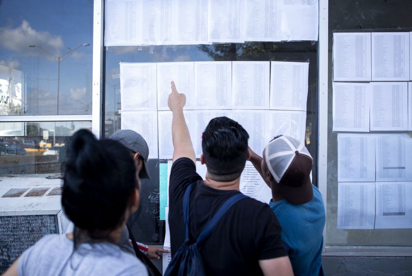 Cuban migrants look at a list of asylum seekers near the Gateway International Bridge in Matamoros, Tamaulipas. Image by Miguel Gutierrez Jr. Mexico, 2019.
