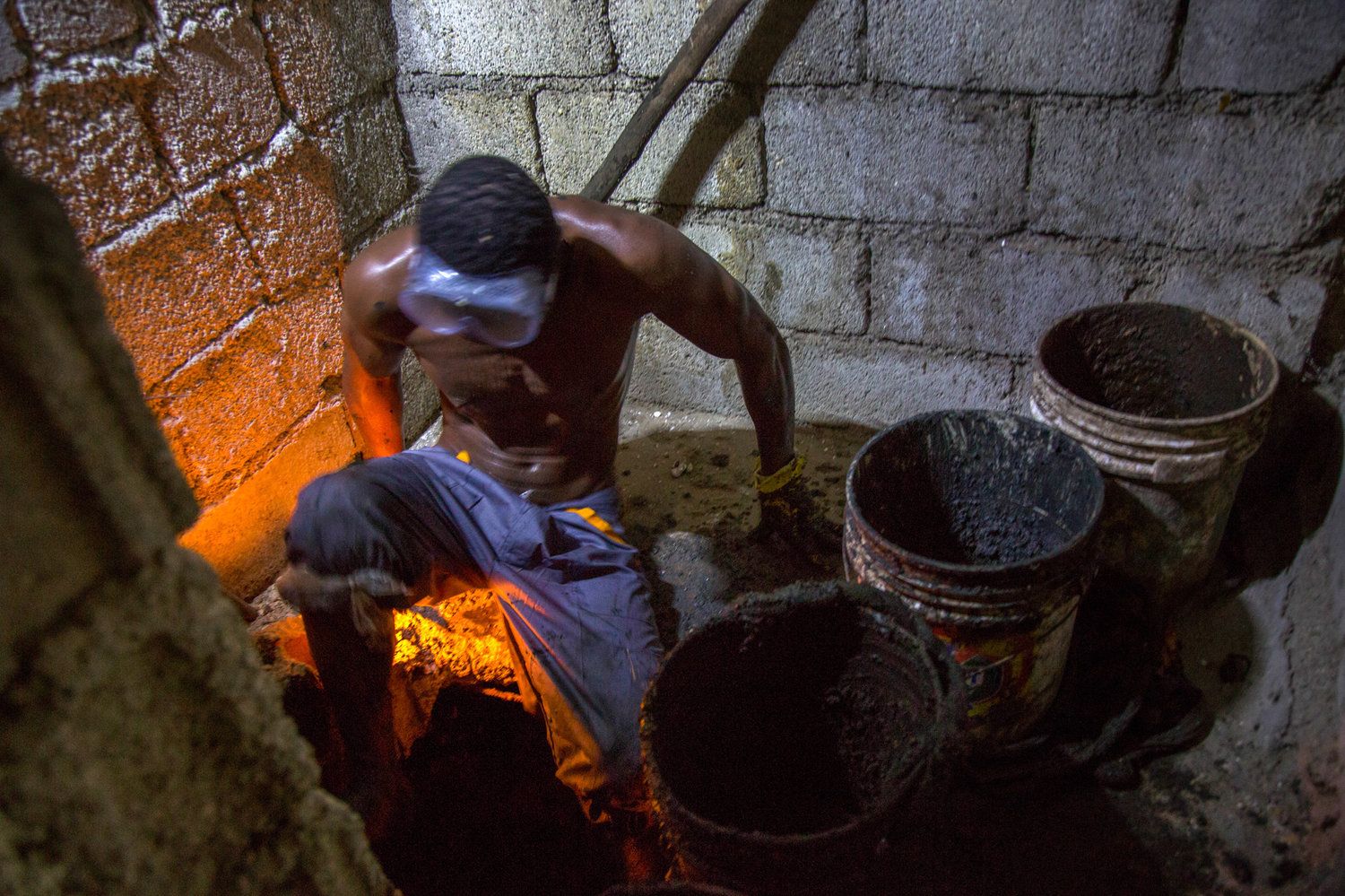 Gabriel Toto, 35, has been working as a bayakou, or latrine cleaner, for a decade. On nights without a journalist watching, he generally works naked. Image by Marie Arago/NPR. Haiti, 2017.