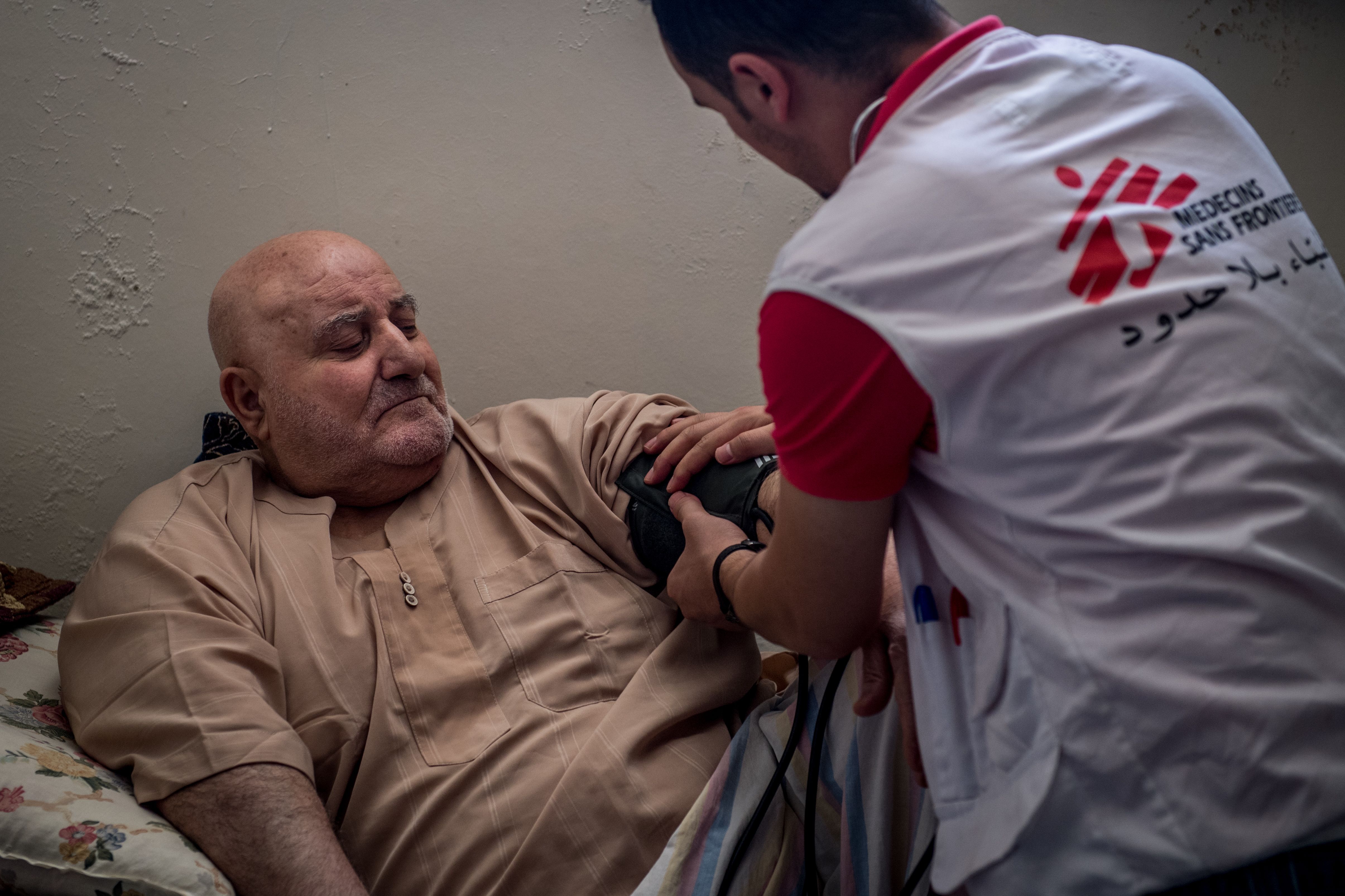 A physician checks on Ibrahim Hassan (left), who lives as a displaced person in Jordan after fleeing the regime in Syria. Image by Neil Brandvold. Jordan, 2017.