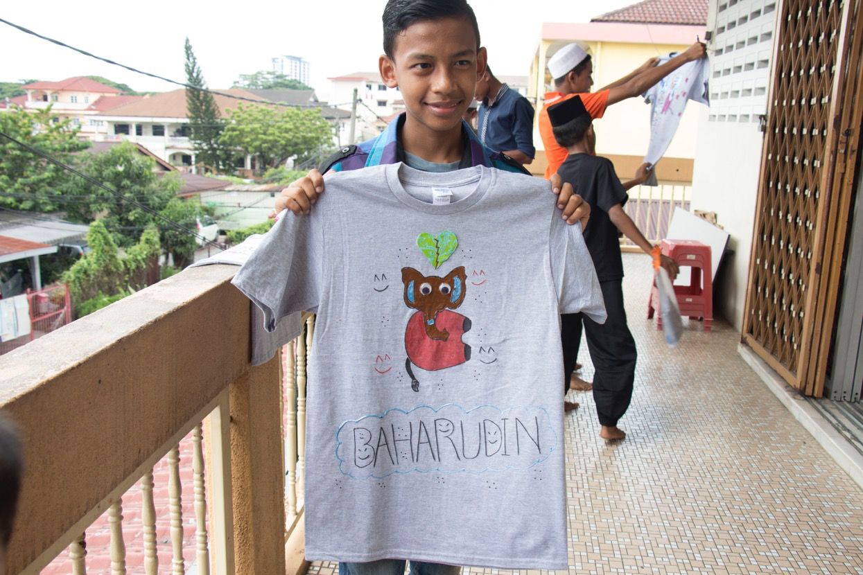 A Rohingya refugee boy holds the tshirt he designed in an arts workshop organized by CreaTee, an NGO that organizes arts workshops for refugee children for confidence-building. Image by Ifath Sayed. Malaysia 2017.