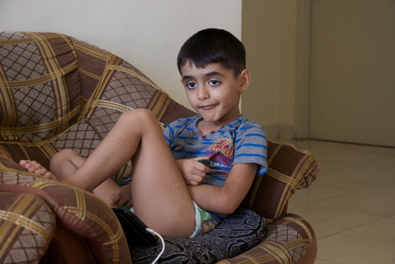 Yahya Al-Zuhairi, a six-year-old autistic boy from Iraq, is sitting on a couch in his home. Image by Ifath Sayed. Malaysia, 2017.