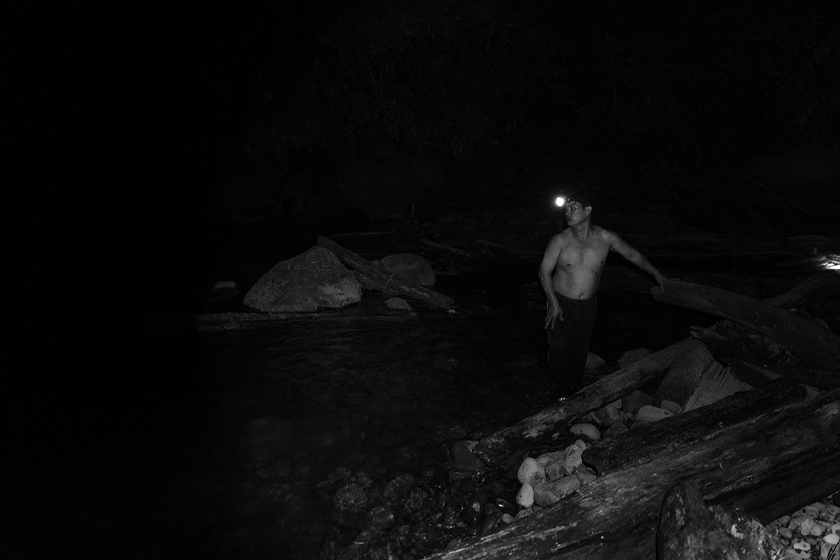 John, Uday's husband, looks for fish after dark. Image by Stuart Franklin/Magnum Photos. Malaysia, 2018.