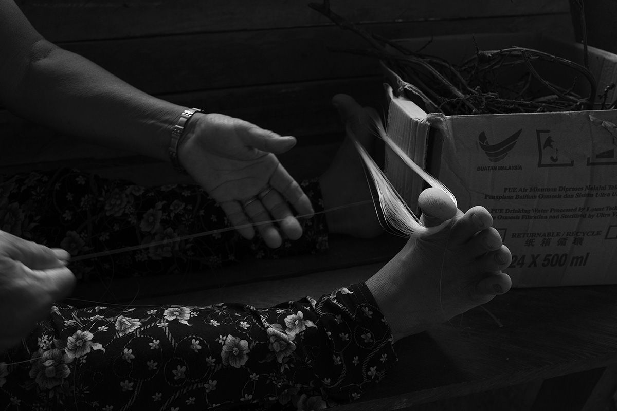 Paya, a Kayan, uses her feet to start weaving a plastic basket handle. Image by Stuart Franklin/Magnum Photos. Malaysia, 2018. 