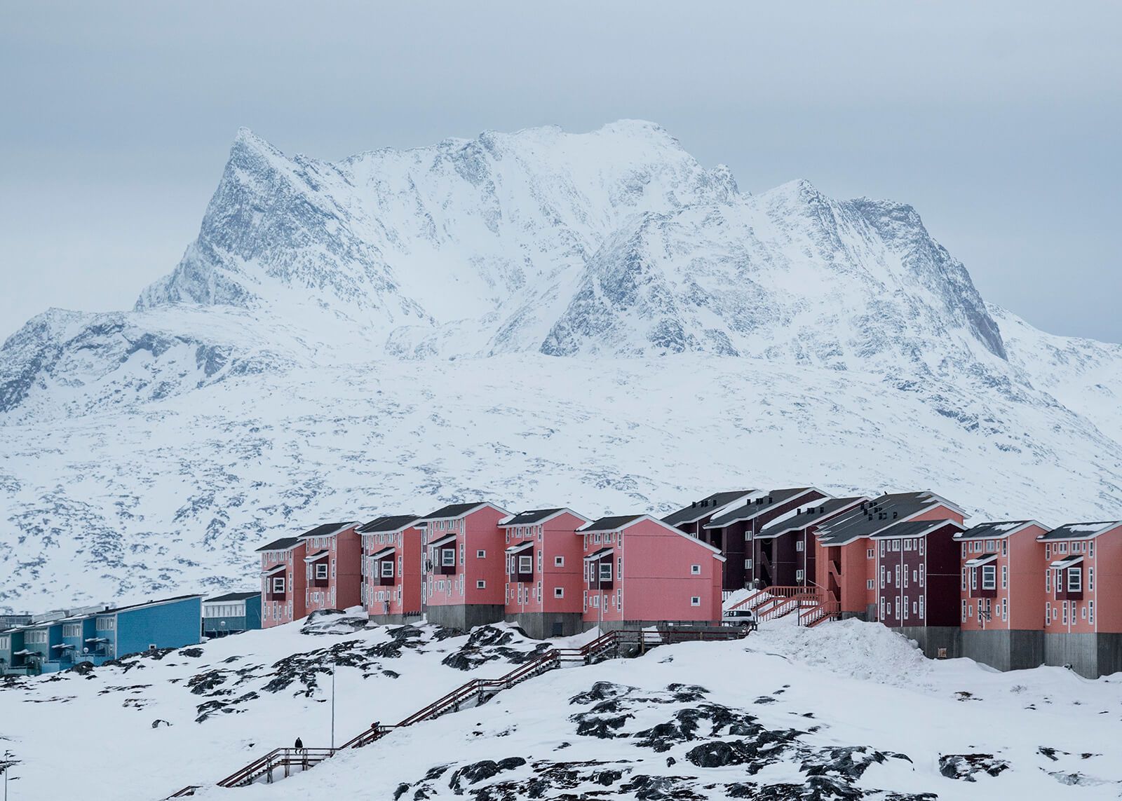 The iconic mountain of Sermitsiaq rises up behind a row of apartment buildings in Nuuk. Image by Jonas Bendiksen/Magnum Photos. Greenland, 2018.