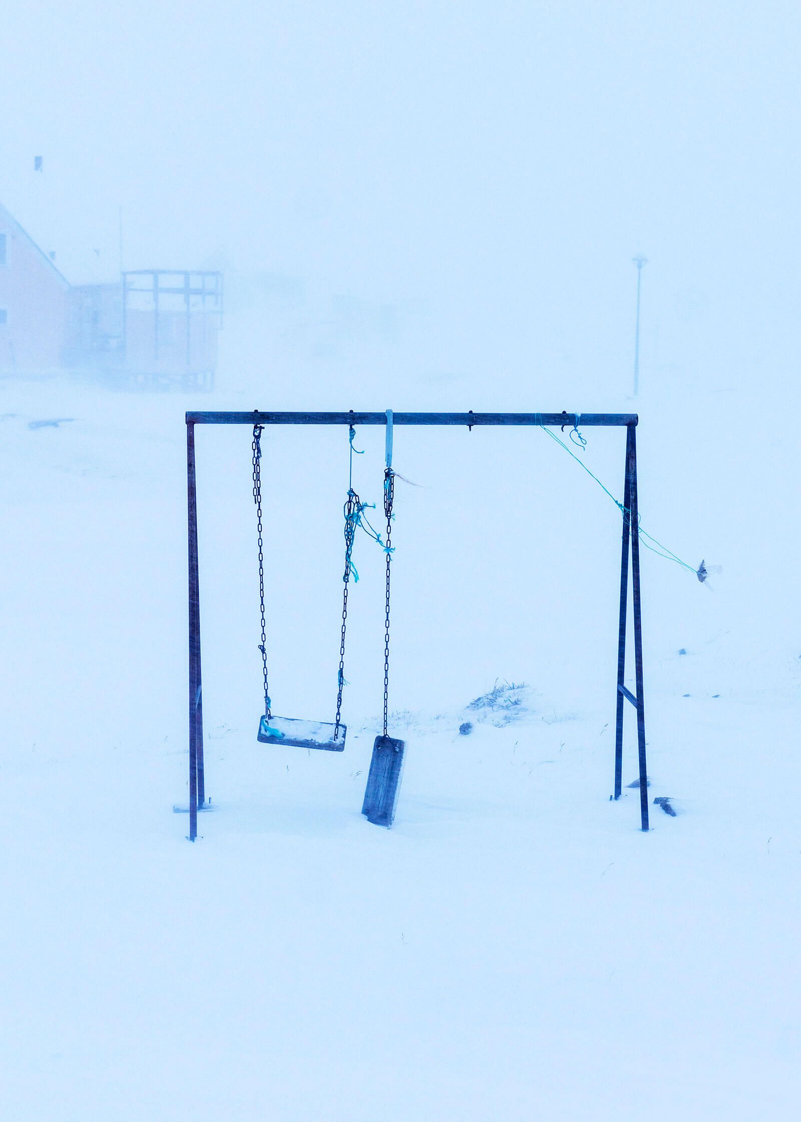 An abandoned playground swing set in the snow in Oqaatsut. Image by Jonas Bendiksen/Magnum Photos. Greenland, 2018.