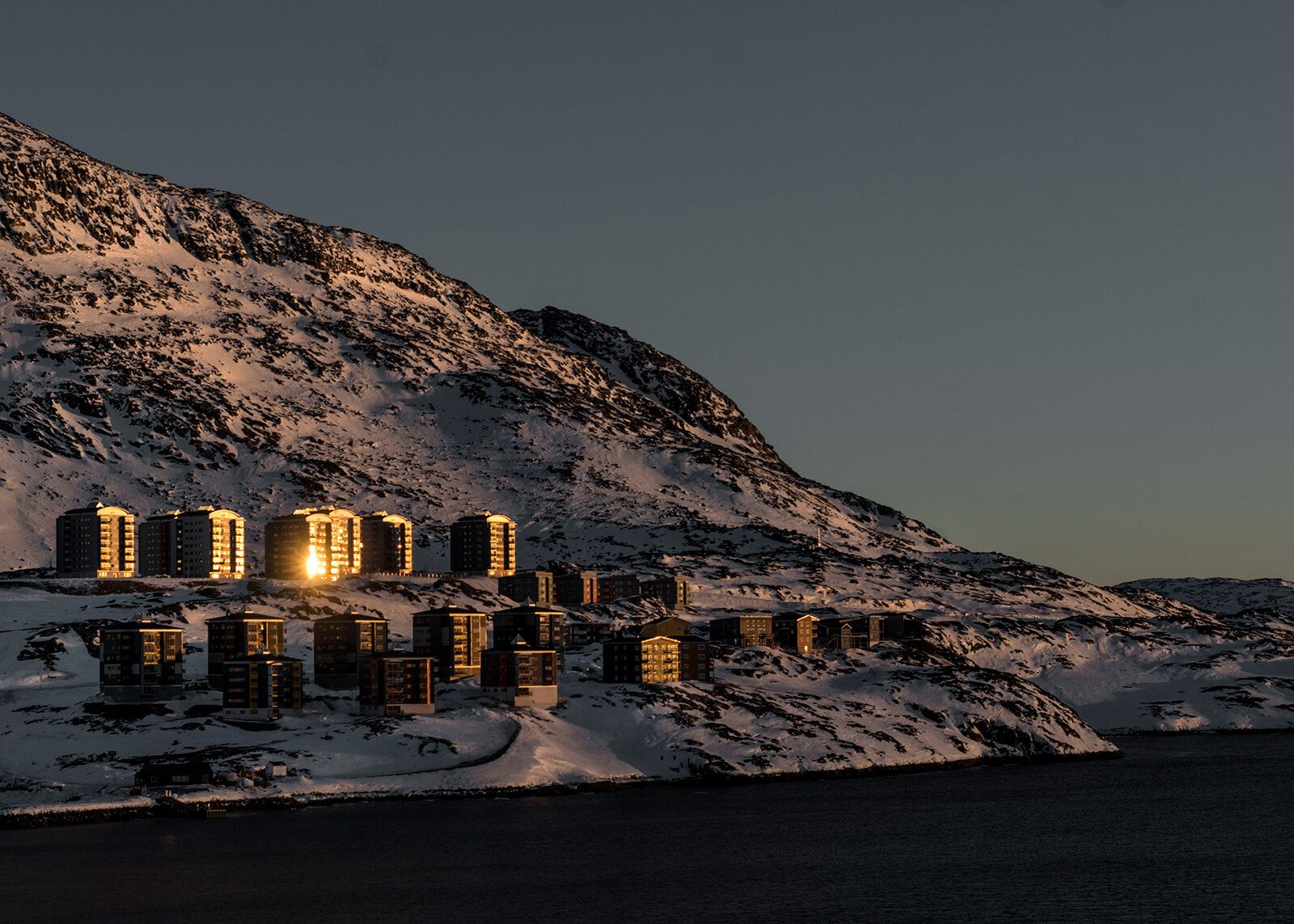New apartment buildings catch the last rays of the sunset in Nuuk, which has a population of 17,500. Image by Jonas Bendiksen/Magnum Photos. Greenland, 2018.