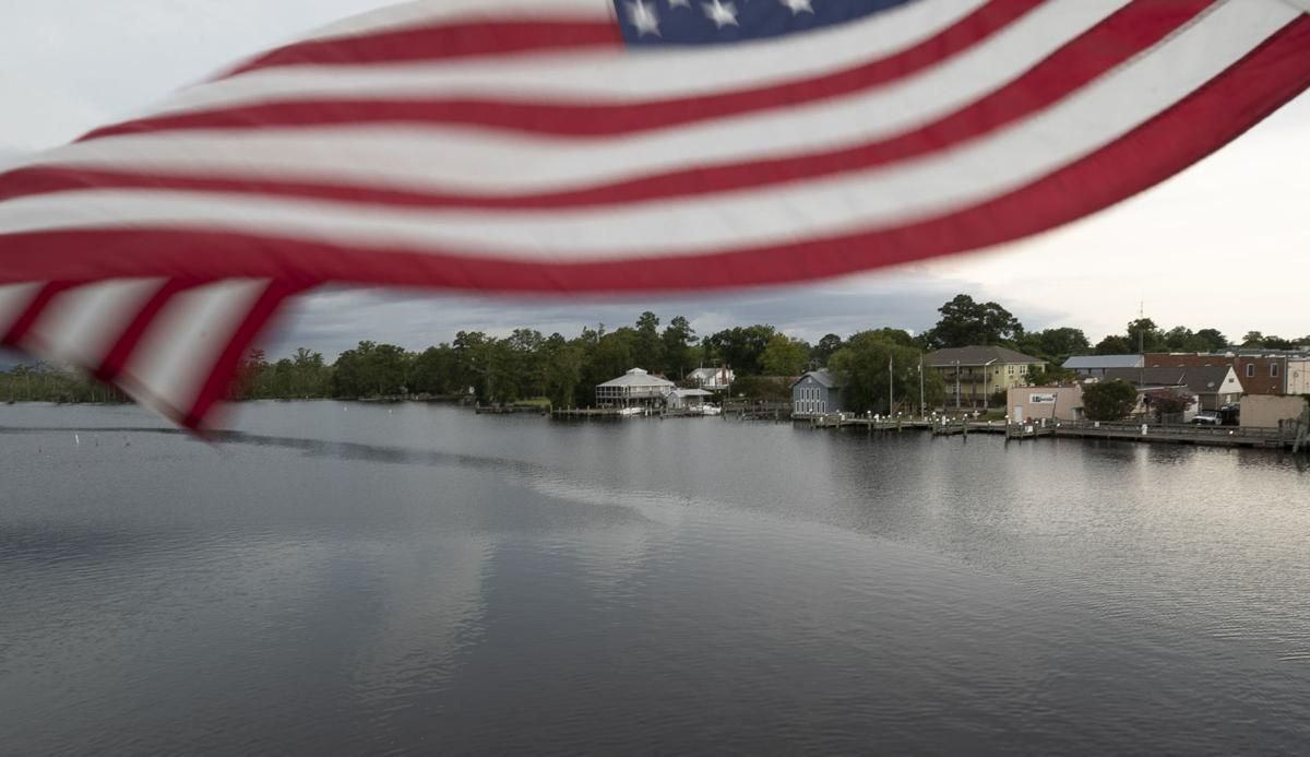 An American flag attached to the bridge over the Scuppernong River frames the waterfront town of Columbia, N.C. on Thursday, July 23, 2020 in Tyrrell County. Image by Robert Willett / The News & Observer / North Carolina News Collaborative. United States, 2020.