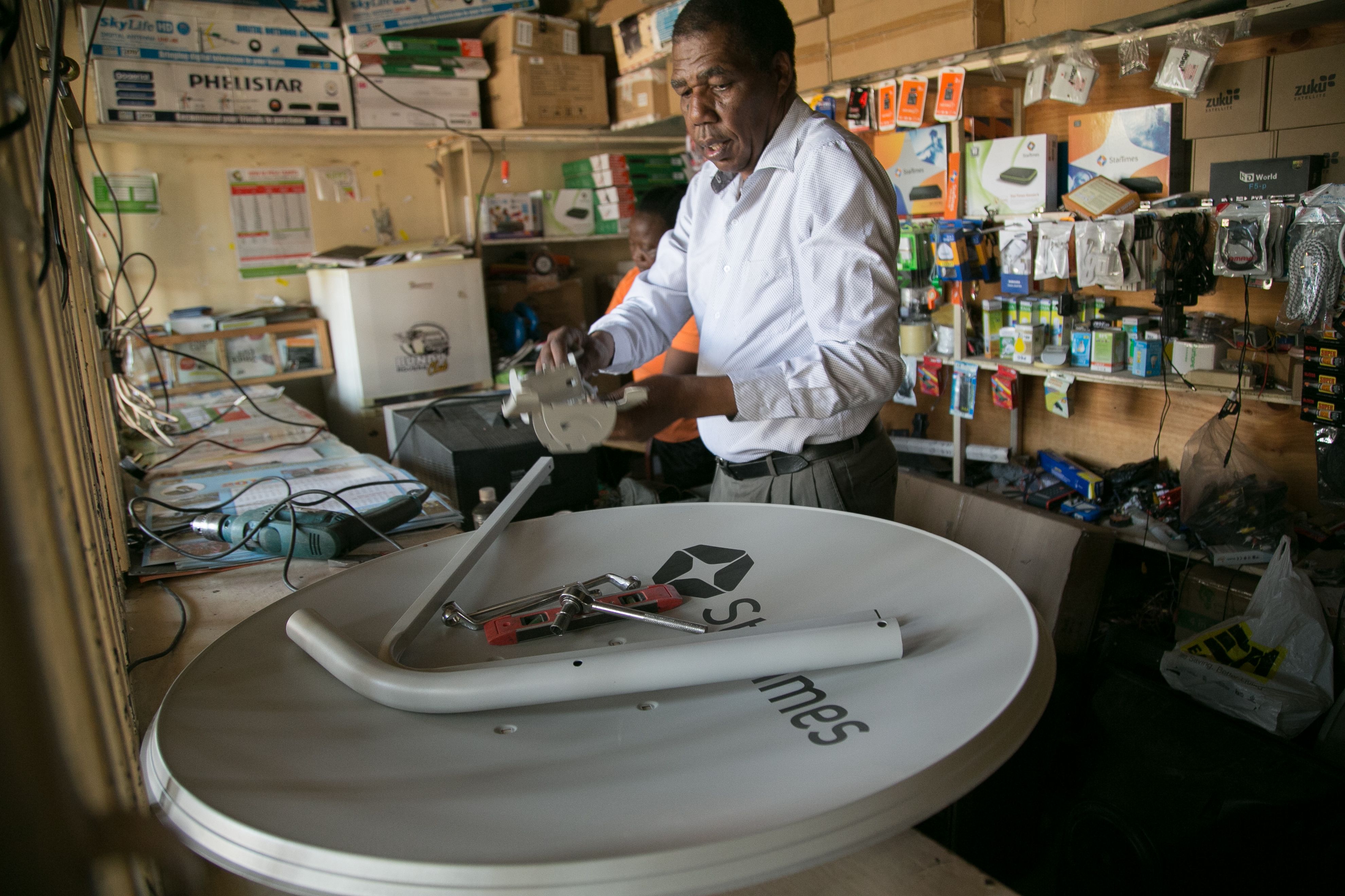  David Mugita builds a StarTimes satellite dish. He is Kajiado’s sole StarTimes agent. Image by Immanuel Muasya. Kenya, 2017 