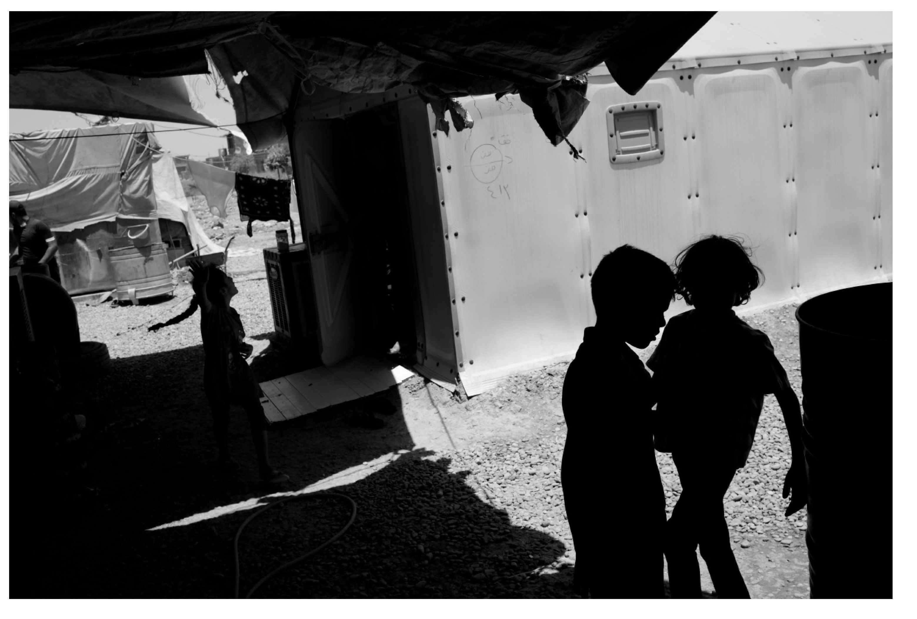 Black and white image of children in silhoutte from an IDP camp in Iraq.