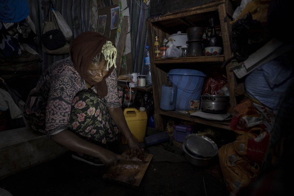 Mother of two Amsale Hailemariam, a domestic worker who lost work because of the coronavirus, prepares food for her family in her small tent in the capital Addis Ababa, Ethiopia on Friday, June 26, 2020. The better-off neighbors who once welcomed her into their homes to cook and clean now turn her away, fearing the virus. “They told me we should avoid contact,” she said. “There was no help I received from them since.” Image by AP Photo/Mulugeta Ayene. Ethiopia, 2020.