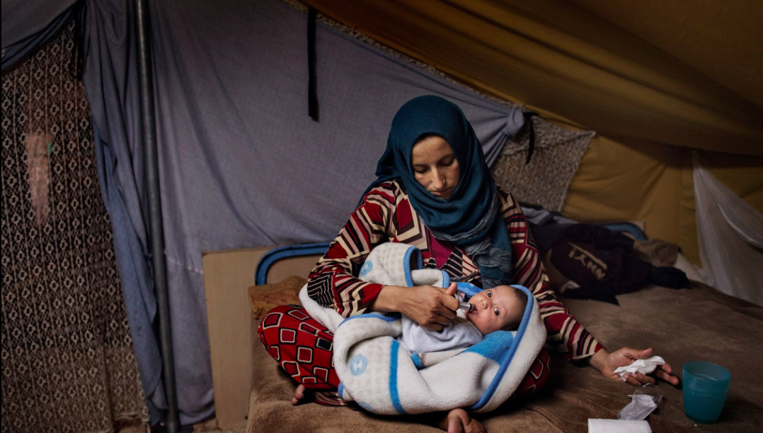 Illham holds her seven week-old baby Faraj in her tent on Nov. 20. Image by Lynsey Addario for TIME. Greece, 2016.