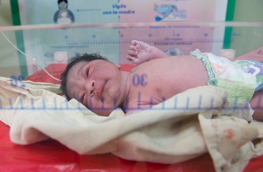 The newborn baby of Venezuelan migrant Emily Semplu peeks her eyes open after having her feet stamped to register her birth on May 5, 2019 in Maicao, Colombia. The baby girl is one of 24,000 babies born to Venezuelan migrants who were born "stateless" in Colombia and were recently granted citizenship by the country's government. Image by Megan Janetsky. Colombia, 2019.