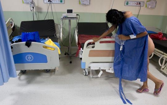 Pregnant Venezuelan migrant Yulianis Rodriguez, grabs the side of a hospital bed as she struggles to cope with the pain of labor without an epidural in Maicao, Colombia on May 5, 2019. She crossed into Colombia alone to give birth to her baby son who was born "stateless" due to Colombia's birthright citizenship laws. Image by Megan Janetsky. Colombia, 2019.