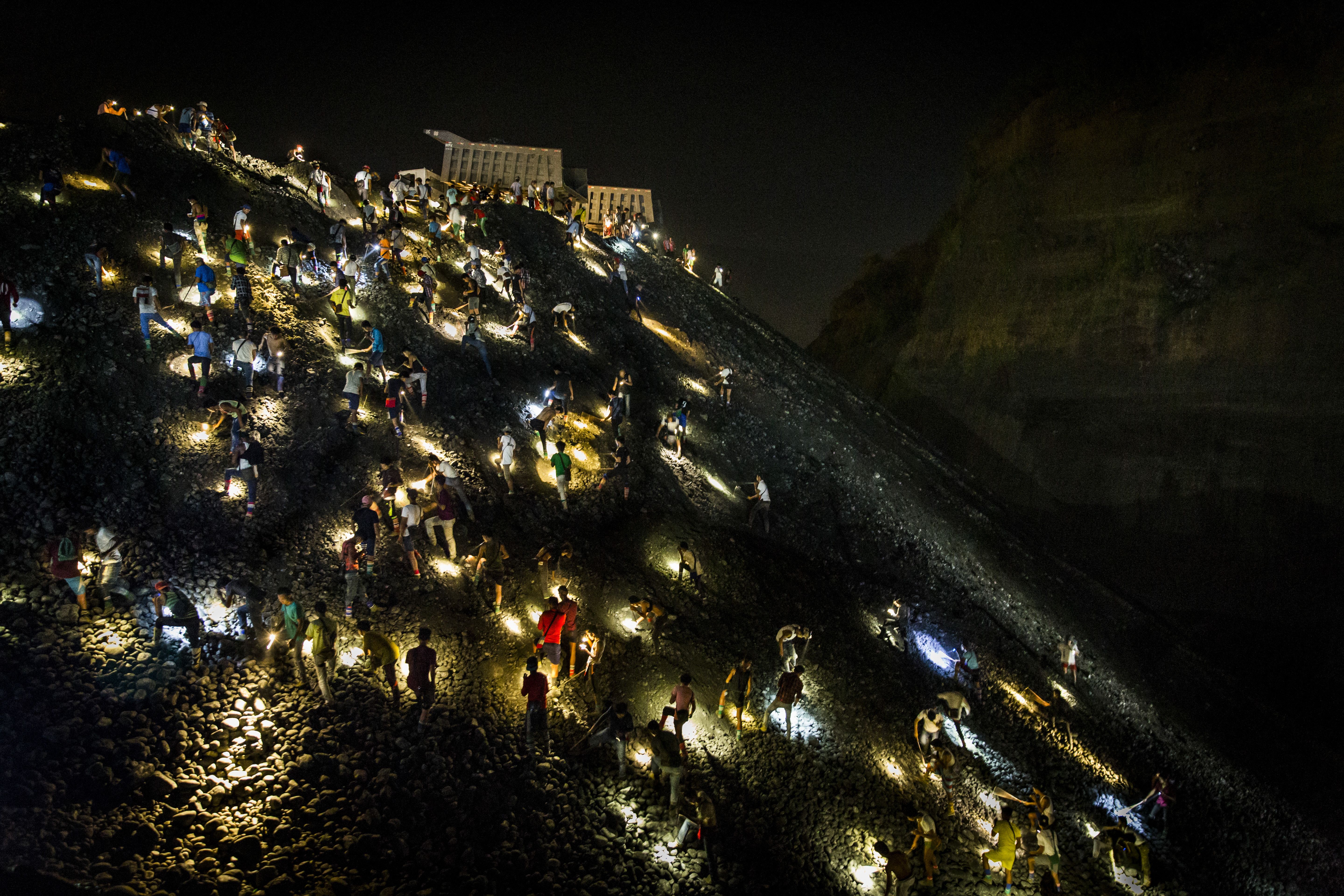 Freelance miners search for jade stones at night with torchlights on a waste site in Hpakant, Kachin State, Myanmar on May 21, 2019. Image by Hkun Lat. Myanmar, 2019.