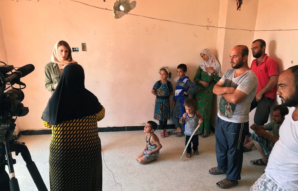 A Syrian family watches as Gayle Tzemach Lemmon conducts an interview. Image by Jon Gerberg/PBS NewsHour. Syria, 2017.