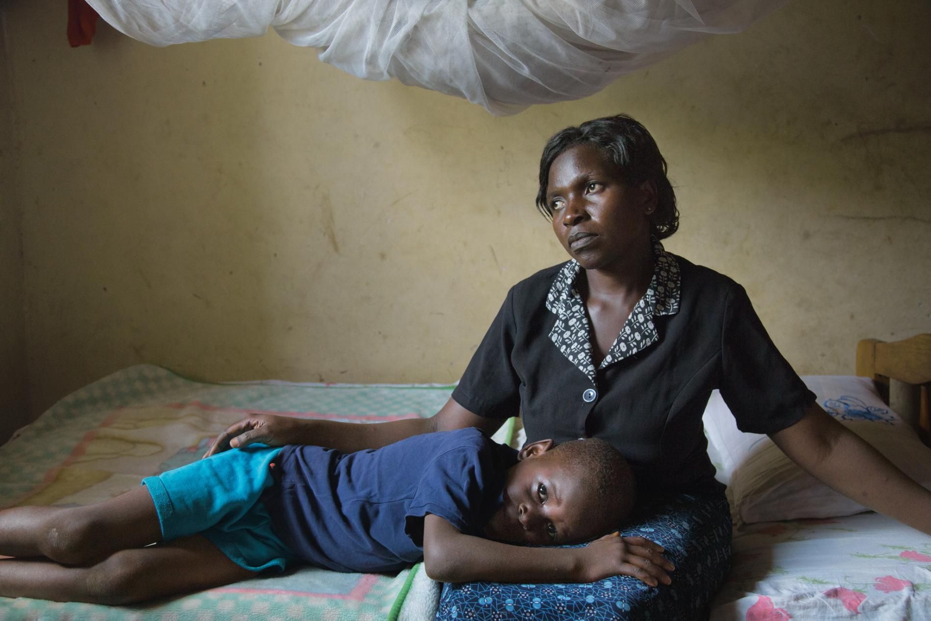 Christine Namatovu and her son Andrew bring solace to each other in the house Namatovu’s in-laws tried to seize when her husband died. Pushing widows off their property is common practice in this region; Namatovu, with the help of lawyers, fought back. Image by Amy Toensing. Uganda, 2016.