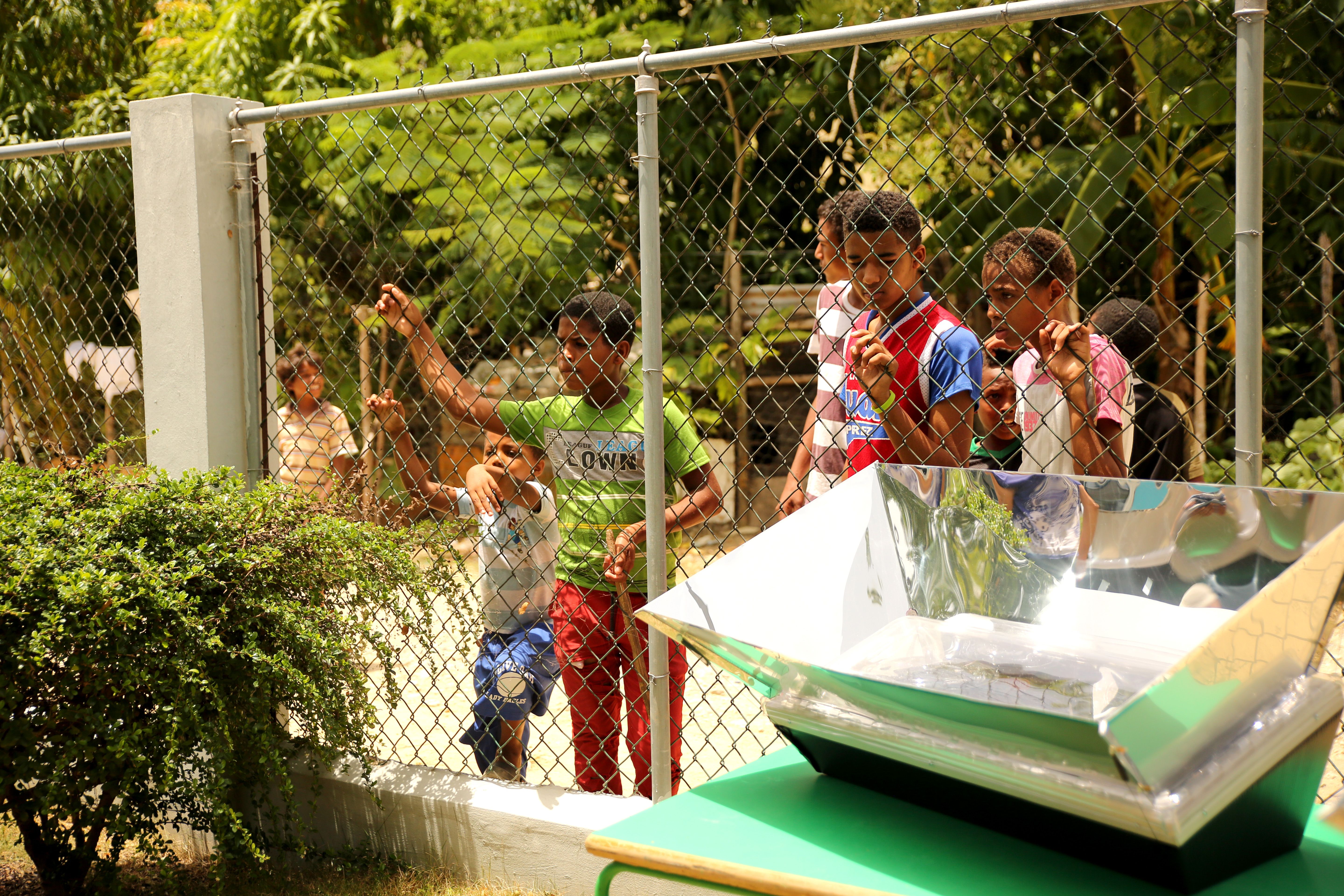 Children watch a solar oven workshop outside the church property