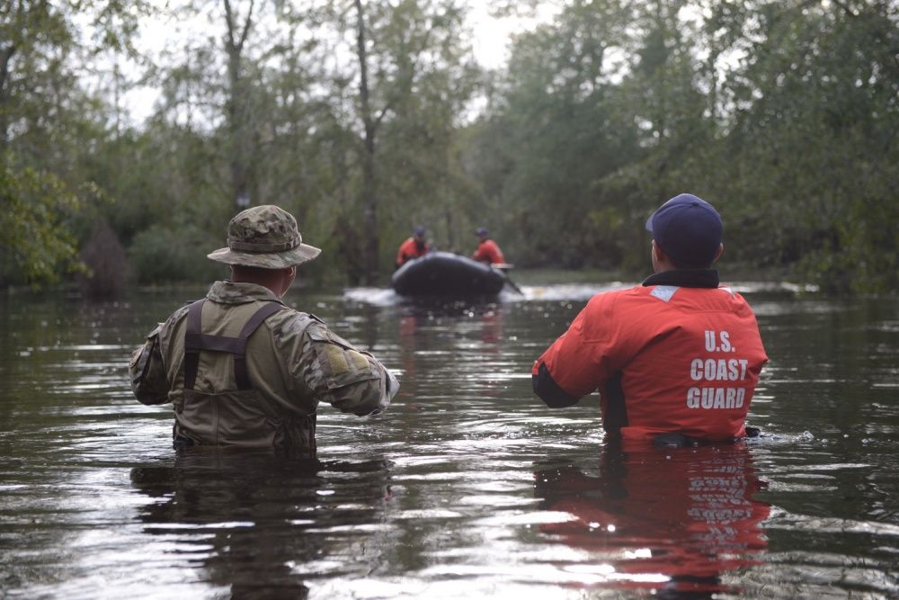 Members of Coast Guard Maritime Safety and Security Team Miami and Coast Guard Tactical Law Enforcement Team South wait to be picked up by their rescue team after completing Hurricane Florence search and rescue operations in Brunswick County, September 16, 2018. Image by Petty Officer 3rd Class Trevor Lilburn. United States, 2018.