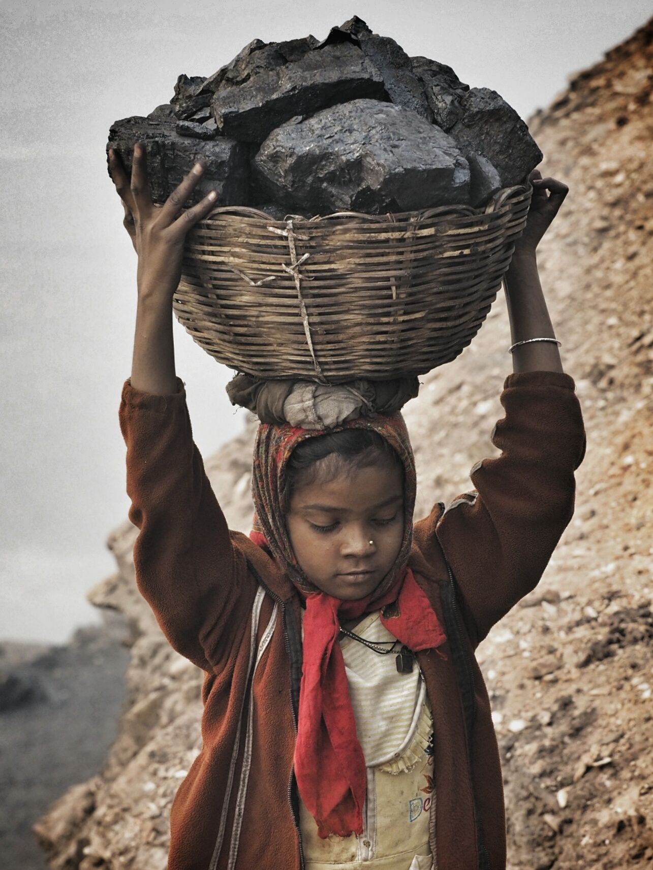 A young girl carries scavenged coal from the bottom of the Alkusha Coalfield.