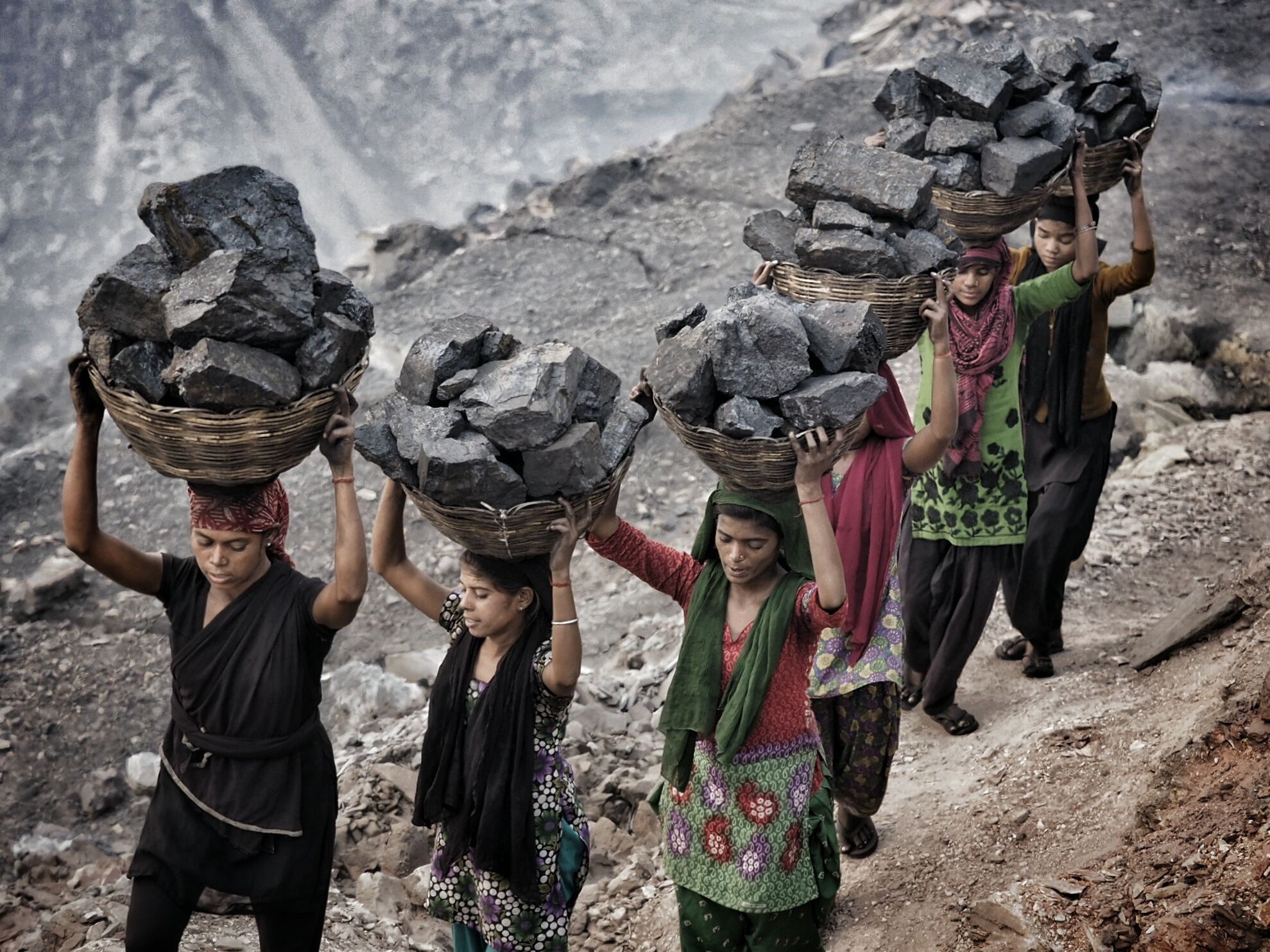 Women and young girls carry scavenged coal from the bottom of the Alkusha Coalfield.