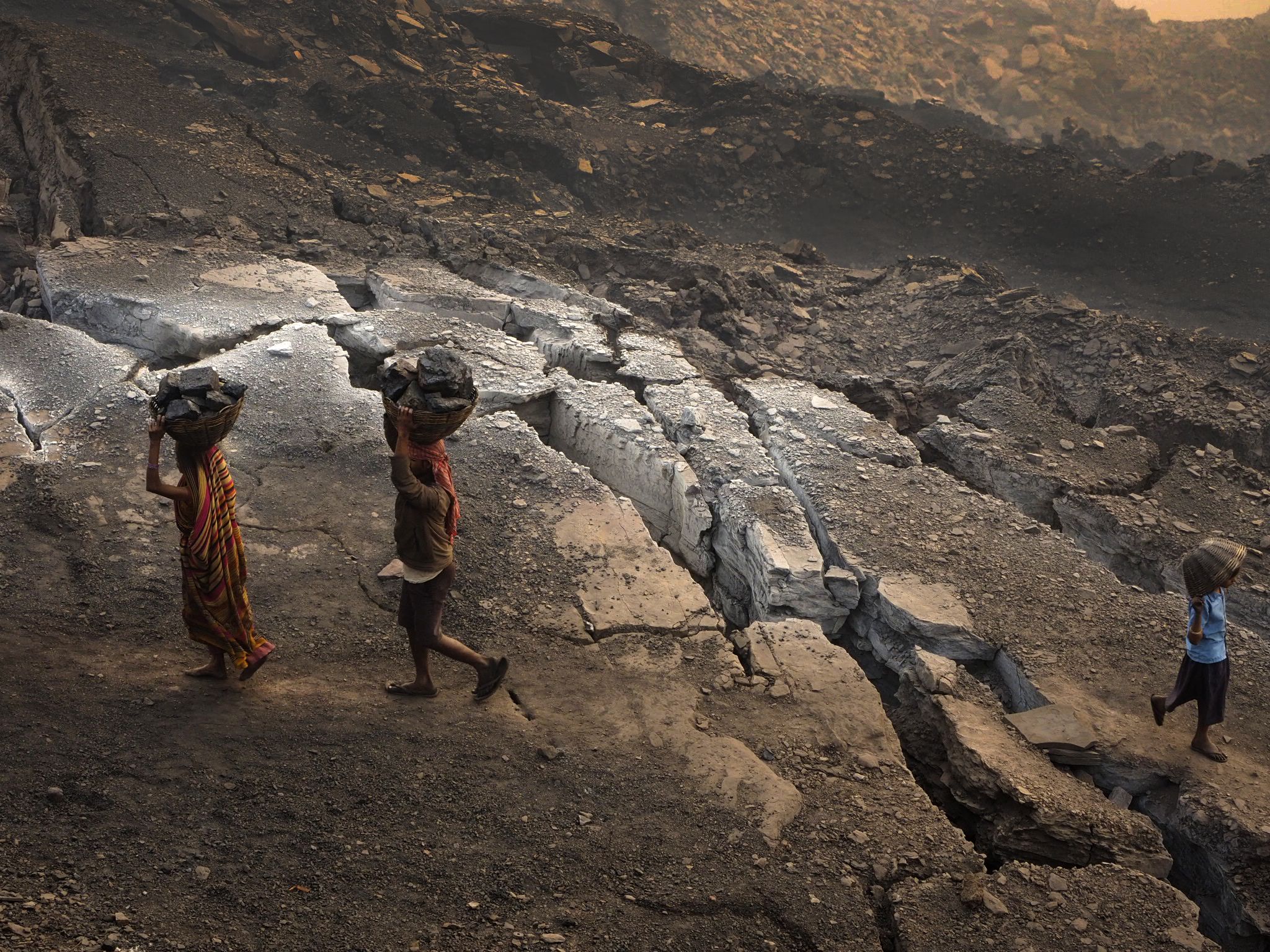 Coal scavengers race past cracks in the earth that emit flames and toxic fumes near Ganshadih.