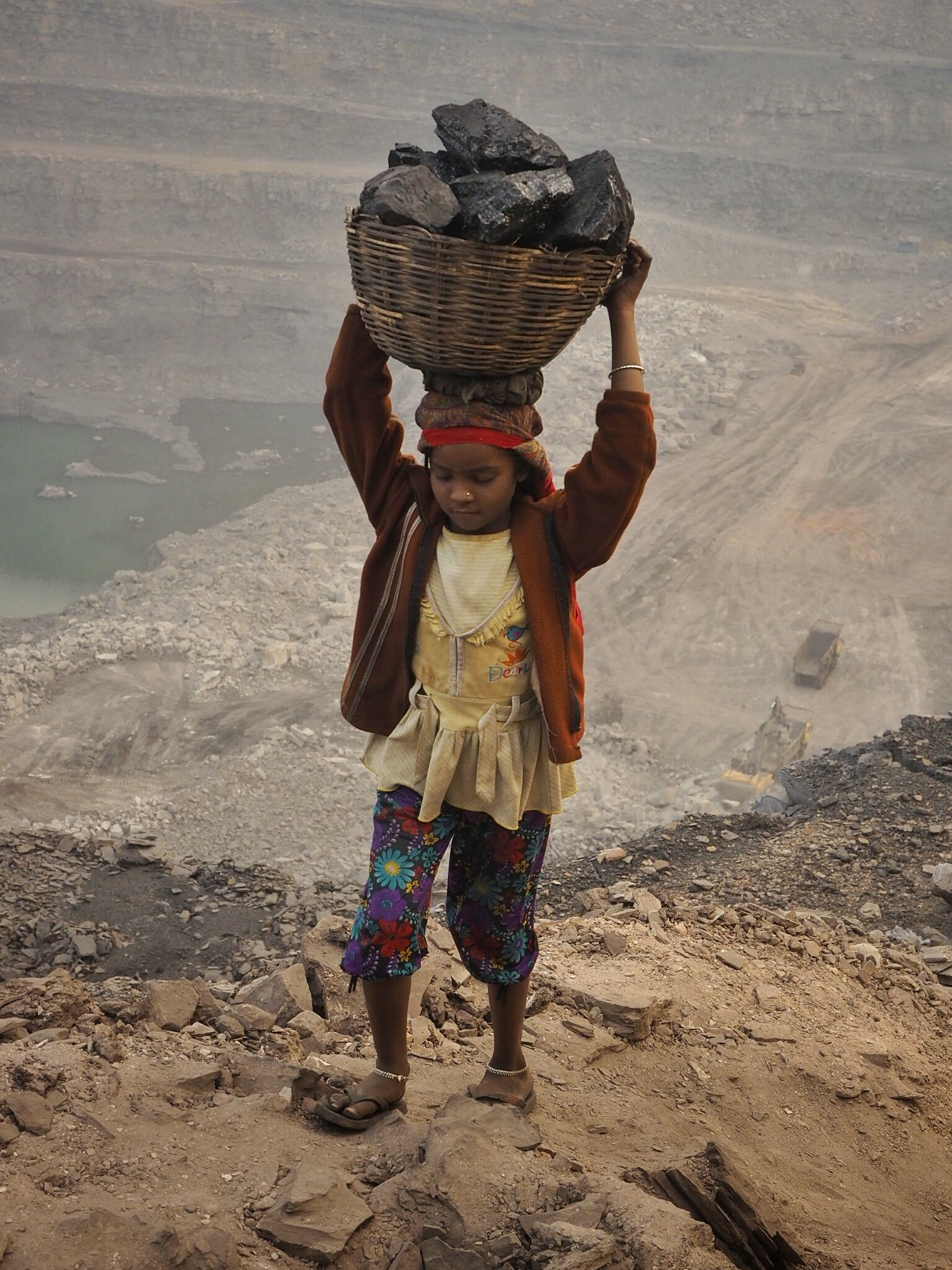 A young girl carries scavenged coal from the bottom of the Alkusha Coalfield.